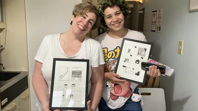 Mother and daughter showing their finished framed manga pages