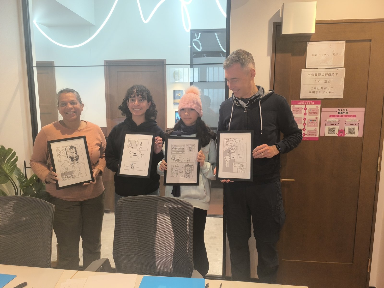 Family of four proudly holding their framed 4-panel manga artworks