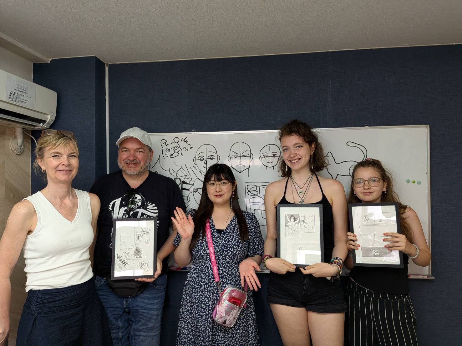 Family and friends proudly holding their framed manga artwork